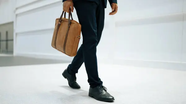 Closeup of professional business man leg walking while holding bag. Cropped image of project manager focus on leg. Traveling, moving, journey, walking, getting a new position, job changing. Exultant.