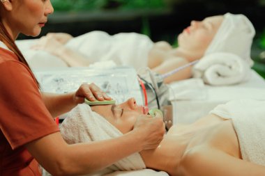 Güzel genç kadınlar profesyonel doktordan yüz masajı alırken spa yatağında yatarlar. Cildi elektrikli yüz makinesiyle çevrili çekici bir kadın. Huzur.