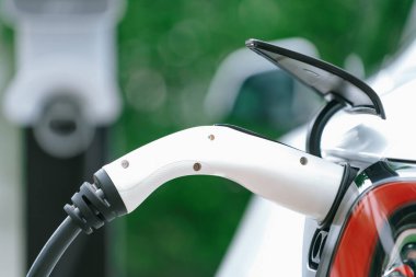 Elektrikli araç portuna bağlı EV şarj prizi kolu şarj istasyonundan şarj oluyor. Modern tasarlanmış EV araba ve daha iyi bir gelecek konsepti için temiz enerji sürdürülebilirliği. Eşzamanlama