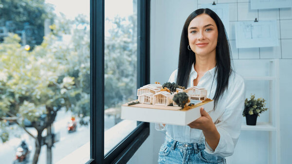 Крупный план квалифицированного молодого красивого кавказского архитектора лифта дом модели левой и правой стороны, чтобы проверить и сосредоточиться на проверке ошибок точки в современном офисе с чертежом. Непорочный.