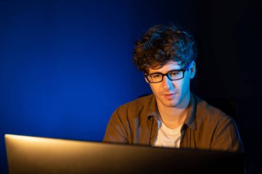 Genç işadamı, Neon Light Modern Ofis 'te yaratıcı bir başlangıç projesi için bilgisayara odaklanıyor. Düşünüyorum da, pazarlama ağı yaratıcıdan pazar kanalı tasarım konseptine çevrimiçi planlama. Toplayıcı.