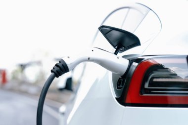 Kapalı EV şarj kolu fişe takıldı veya elektrikli arabaya bağlandı, EV araba aküsünü temiz çevre için sıfır CO2 emisyonu ile alternatif ve sürdürülebilir enerjiyle şarj etti. Kalıcı