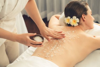 Lüks spa salonlarında sıcak mum ışığında cilt bakımı yaptıran kadın müşteri. Sağlık Spa vücut fırçasında tuz temizleme güzellik tedavisi. Sessiz.