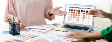 Yaratıcı grafik tasarımı seçici renkler sunarken, yönetici de masadaki uygun renkleri renk paletleriyle karşılaştırarak modern ofiste grafiksel malzeme dağılımı yapıyor. Değiştirilmiş.