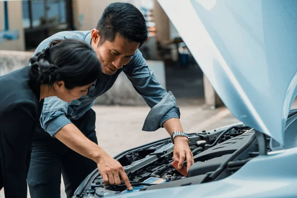 男性は女性が車の問題を解決するのを助けます 彼は損傷した部分を修理するために車のフードをポップアップしました インタビュー — ストック写真