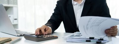 Şirket muhasebecisi, mali veri raporuna dayanarak vergi iadelerini hesaplamak ve en yüksek seviyeye çıkarmak ve finansal performansı artırmak için hesap makinesi kullanır. Panorama 'daki modern muhasebe. Kurnaz.
