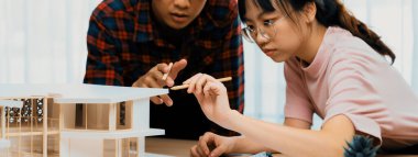 Akıllı mimar mühendis ve iç mimar birlikte çalışıyor ve ev modelini ölçmek için plan ve mimari ekipmanlarla toplantı masasında cetvel kullanıyor. Takım çalışması konsepti. Filizlenen.