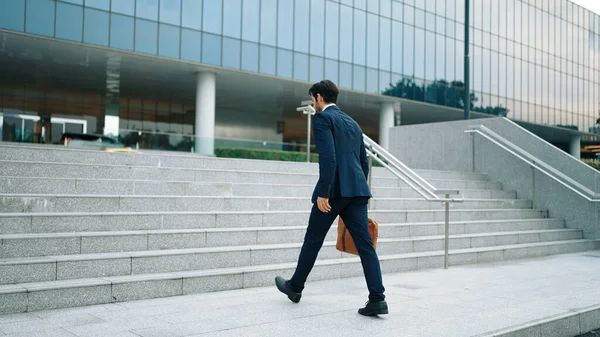 Skilled business man walking up stairs at park or city while holding bag in the hand Professional project manager going to workplace. Represent growth, getting promotion, increasing skill. Exultant.