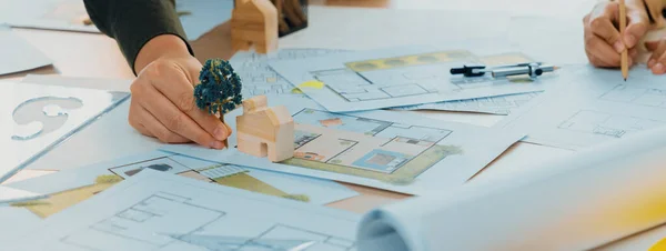 Sustainable eco house blueprint was placed on meeting table with architectural paper work scatter around during skilled architect discussion about green design of green city. Closeup. Delineation.