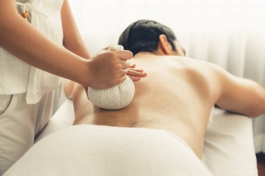Sıcak bitkisel top spa masaj vücut tedavisi, masör erkek vücuduna nazikçe şifalı bitki torbası bastırıyor. Aromaterapi dinlenme sükuneti ve sükuneti kaplıca salonundaki atmosferi aydınlatıyor. Sessiz.