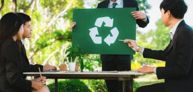 Doğa planlaması ve geri dönüşümlü atıkları azaltmak ve yeniden kullanmak suretiyle daha yeşil bir çevre için geri dönüşüm stratejisi üzerinde kafa yormak üzere açık ofiste toplanan bir grup iş adamı. Döngü