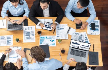 Üst düzey iş analist grubu toplantı masasındaki finansal veri raporunu analiz ediyor. İş zekası analizine göre çizelge ve grafik paneli. Çok titiz.