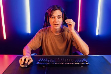 Kazanmak için çevrimiçi oyun oynayan akıllı flama makinesinin sunucu kanalı, neon ışıklı odada seçilen takım yarışması için izleyicilerle birlikte canlı yayında canlı yayında kulaklık takıyor. Bireysel.