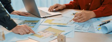 Dizüstü bilgisayar kullanırken ev yapımı tasarımı hakkında iş arkadaşıyla tartışan yetenekli bir mimarın portresi. Profesyonel mühendisler ev planını dikkatlice seçerler. - Yakın çekim. Tanımlama.