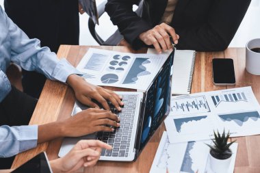 Çok ırklı analist ekibi toplantı masasındaki finansal verileri analiz etmek için BI Fintech yazılımı kullanıyor. Finansal konsol veri ekranında pazarlama göstergesi için analiz edilmiş grafikle birlikte. Uyum