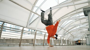 Hipster 'ın kulaklık taktığı ve enerjik adımlar atarken hip hop dinlediği bir sahne. Break dansçı dondurucu poz veriyor. Sokak dansı. Modern yaşam tarzı. Açık hava sporu 2024. Yumuşak bir şekilde..