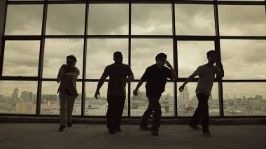 Yetenekli koreograf grubunun gökyüzü dövüşçüsüyle dans ederken çekilmiş siluet fotoğrafı, şehir manzarası arka planı. Genç hipster takımı dans gösterisi. Sepia filtresi. Gölge. Açık hava sporu 2024. ÇalışmaComment.
