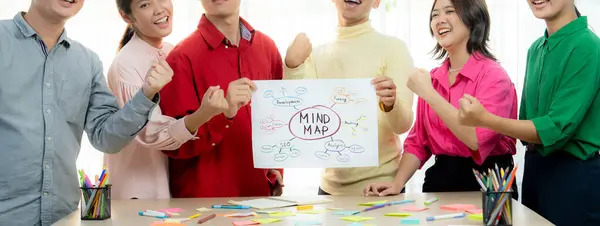 A cropped image of successful businesspeople presents new product marketing strategy using a mind map. Young creative business team brainstorm marketing idea together at modern office. Variegated.