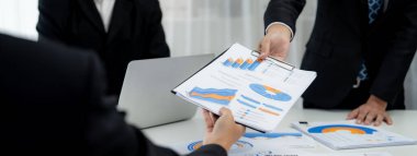 Grup toplantısındaki iş adamları resmi kıyafet paylaşımı fikrine sahipler. Şirketin yaratıcı çalışma alanındaki kar raporunu tartışıyorlar. Grup toplantısı masasında yakın çekim yapmak için. Konuşma .