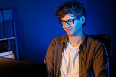 Neon Light Modern Ofis 'te yaratıcı bir başlangıç projesi için bilgisayara odaklanan gülümseyen genç iş adamı. Düşünüyorum da, pazarlama ağı yaratıcıdan pazar kanalı tasarım konseptine çevrimiçi planlama. Toplayıcı.