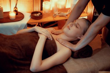 Beyaz kadın müşteri stres önleyici spa masajının keyfini çıkarıyor ve lüks otel ya da otelde sıcak mum ışığında güzellik teniyle eğleniyor. Sessiz.