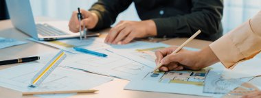 Profosyonel mühendisin, plan, dizüstü bilgisayar ve mimari ekipmanların etrafa saçıldığı toplantı masasının planlarını ölçmek için bölücü kullandığı kırpılmış bir görüntü. - Yakın çekim. Tanımlama.