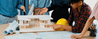 Mimari takım analizi ve ev modeli, plan ve mimari ekipmanlarla toplantı masasında ev inşaatı hakkında beyin fırtınası. Yaratıcı tasarım ve takım çalışması. Filizlenen.