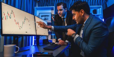 Borsa simsarları panorama manzaralı yüksek kar tablosu yatırımlarına bakıyor, geceleri monitörde analiz ediyorlar. İş yerinde finansal teknoloji gelişimini neon ışığında tartışma kavramı. Satılabilir.