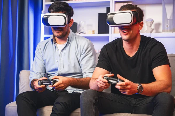 Buddy friend gamers playing video game using joysticks and VR headset of virtual technology in reality in studio room with neon blue light. Comfy living indoor with cheerful fighting winner. Sellable.