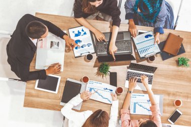 Modern ofisteki iş adamları ve iş kadınlarıyla grup toplantısındaki iş adamlarının en üst düzey görüşü, masada dizüstü bilgisayar, kahve ve belge ile. Kurumsal şirketler uds