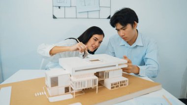 Mimari belge ve ev modeli ile toplantı masasının üzerindeki ev modelini ölçerek birlikte çalışan profesyonel mimar ekibinin yakın plan görüntüsü. Yaratıcı tasarım konsepti. Tertemiz..