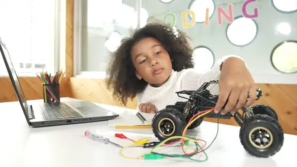 スマートアフリカの女の子は ラップトップ設定やプロンプトコードを書いている間 ワイヤーを使用しながらロボット車を構築します Stem技術オンライン教室でコンピュータに取り組む熟練した女性学生 エラー — ストック写真