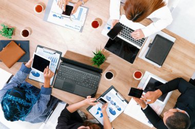 Modern ofisteki iş adamları ve iş kadınlarıyla grup toplantısındaki iş adamlarının en üst düzey görüşü, masada dizüstü bilgisayar, kahve ve belge ile. Kurumsal şirketler uds