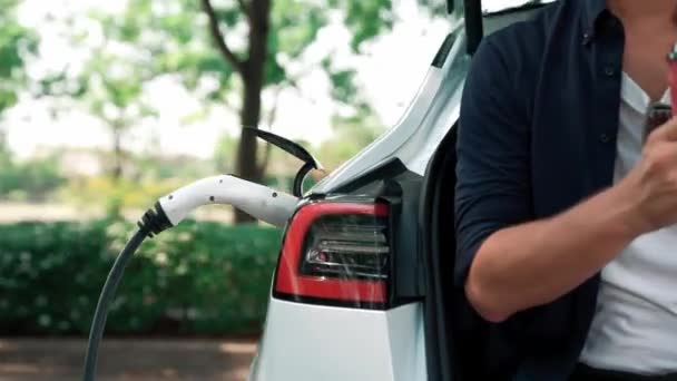 Człowiek Ładuje Akumulator Samochodu Elektrycznego Podczas Podróży Samochodem Naturalnym Lesie — Wideo stockowe