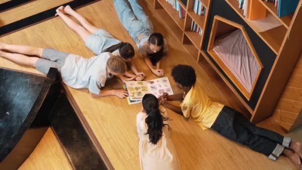 図書館で本を読んでいる間 さまざまな子供たちのグループが円に横たわっています 興味のあるトピックを指し 素敵な友達と話しながら 雑誌を共有する女の子のトップビュー イスラーム主義 — ストック動画