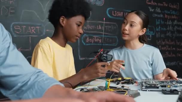 Stemクラスで教師プログラミングエンジニアリングコードをプログラミングしながら 若い学生の固定コントローラー 電子ツールとブラックボードを使用しながら インストラクターハンドタイピングコンピュータの閉鎖 イスラーム主義 — ストック動画