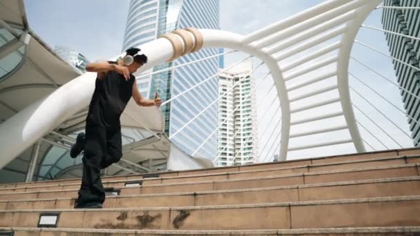 亚洲嬉皮士头戴耳机听嘻哈风格和移动到音乐 专业的年轻霹雳舞蹈演员用低角度相机跳舞时 可以走路 也可以走上楼梯 2024年户外运动 神气活现 — 图库视频影像