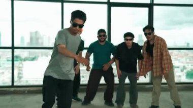 Profesyonel hipster, çeşitli çok kültürlü arkadaşlarıyla birlikte adım atıp dans ediyor. Gökyüzü dövüşçüsü ve şehir manzaralı pencerenin yanında duruyor. Break dans. Açık hava sporları konsepti 2024 hiphop..