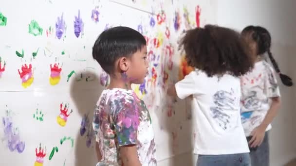 在艺术课上 多样化的学生在色彩斑斓的墙上用手触摸 快乐的多文化朋友玩耍着 喜欢用手去画墙壁创作活动的概念 Erudition — 图库视频影像