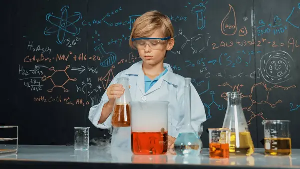 スマートな少年は 慎重に保持し 見ている間 実験室ビーカーの混合化学液体を検査します コカシアの子供は化学の授業やStemの科学クラスで実験を行うことに焦点を当てています エラー — ストック写真