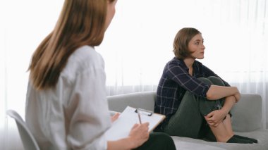 Psikologla ruh sağlığı terapisi gören üzgün travma sonrası stres bozukluğu olan bir kadın. Yaşam sonrası depresyon veya keder. Hayal kırıklığına uğramış genç bir kadın klinikteki duygular hakkında prim psikoloğuyla konuşuyor.