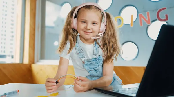 Dziewczyna Nosząca Słuchawki Podczas Nauki Sprzętu Patrząca Kamerę Białe Dziecko — Zdjęcie stockowe