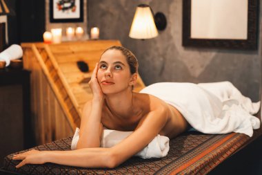 Beyaz havluyla beyaz kadın portresi kaplıca salonundaki rahat ve huzurlu sauna dolabının önündeki kaplıca yatağında yatıyor. Kapatın. Yan görüş. Huzur.