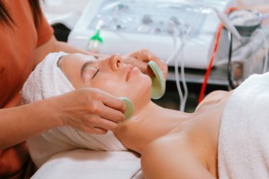 Güzel genç kadınlar profesyonel doktordan yüz masajı alırken spa yatağında yatarlar. Cildi elektrikli yüz makinesiyle çevrili çekici bir kadın. Huzur.