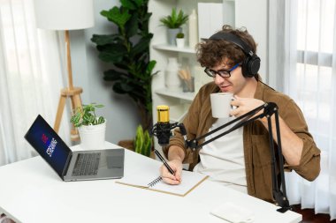 Etkilenen kişinin sunucu kanalı, sosyal medyada dinleyicilerle birlikte kahve içerken dizüstü bilgisayarla bilgi notu yazıyor. Rahat stüdyo modern ev ofisinde radyo çevrimiçi yaşam tarzları kavramı. Toplayıcı.