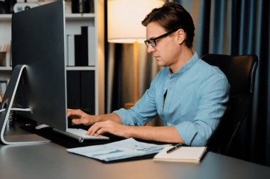 Akıllı iş adamı iş paragrafı dinamik pazarlama analizi planını analiz ediyor. Kağıt kağıtları ve bilgisayar monitörü raporlarını gece evdeki belge verileriyle karşılaştırmak için hazırlıyor. Bireysel.