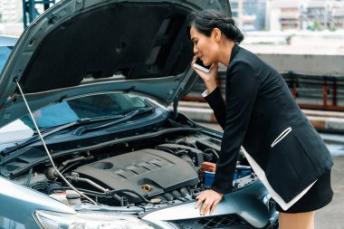 Arabası arızalı genç bir iş kadını yol yardımı için cep telefonu kullanıyor. Seyahat ve ulaşım aracı sorunu. uds
