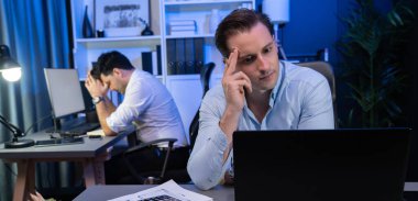 Baş ağrısı olan stresli iş arkadaşı gece vakti yeni bir proje üzerinde çalışıyor, e-posta bekliyor kazanma teklifi veren müşteri firması için geri gönderiliyor. Neon mavi ışık modern ofis üzerinde çalışma kavramı. Satılabilir.