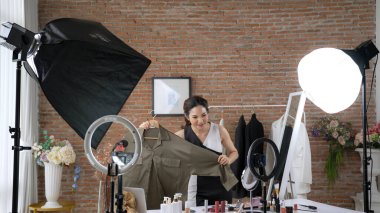 Kadın nüfuzlu kişi video görüntülerini canlı yayınlıyor. Sosyal medya ya da blog. Stüdyo ışıklandırması olan mutlu genç bir kız pazarlama için internet üzerinden yayın yapıyor..