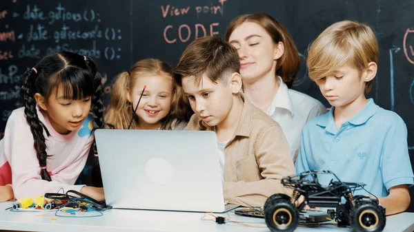 ラップトッププログラミングエンジニアリングコードとライティングプログラムを使用して少年を閉じ ブラックボードのStemテクノロジークラスルームでコントローラを保持する多様な子供のグループが迅速に書かれました エラー — ストック写真